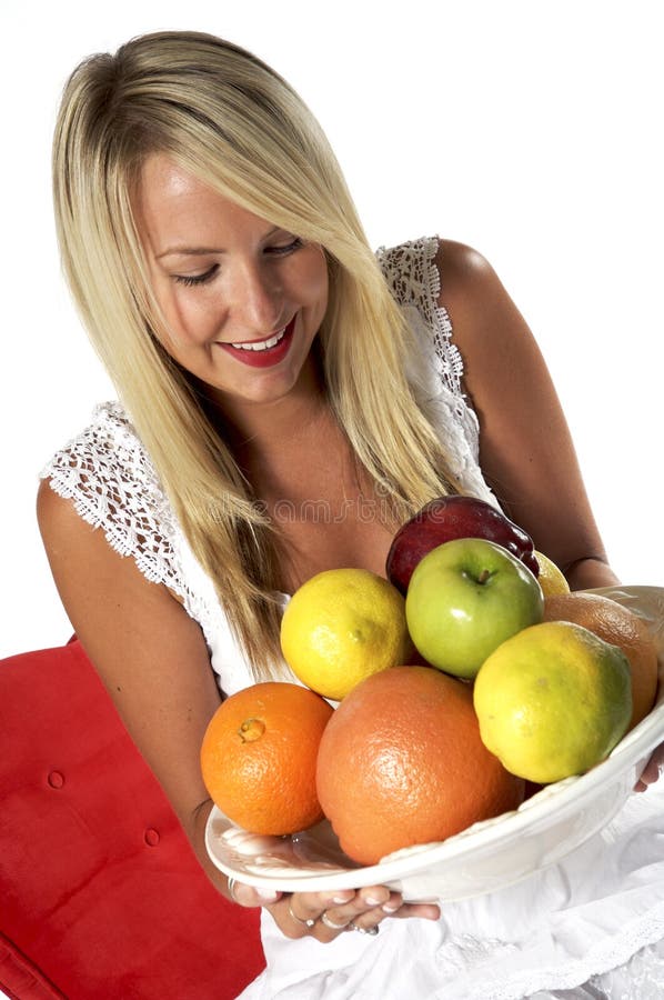 Healthy, luscious blond, with delicious bowl of fruit, sitting on a red chair, with white background. Healthy, luscious blond, with delicious bowl of fruit, sitting on a red chair, with white background