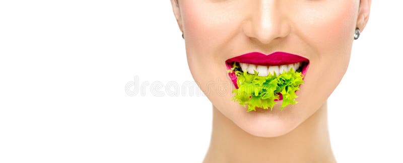 Beautiful healthy girl eating raw vegan food and smiling. Lips. Beauty young fashion woman eats green fresh lettuce salad leaf