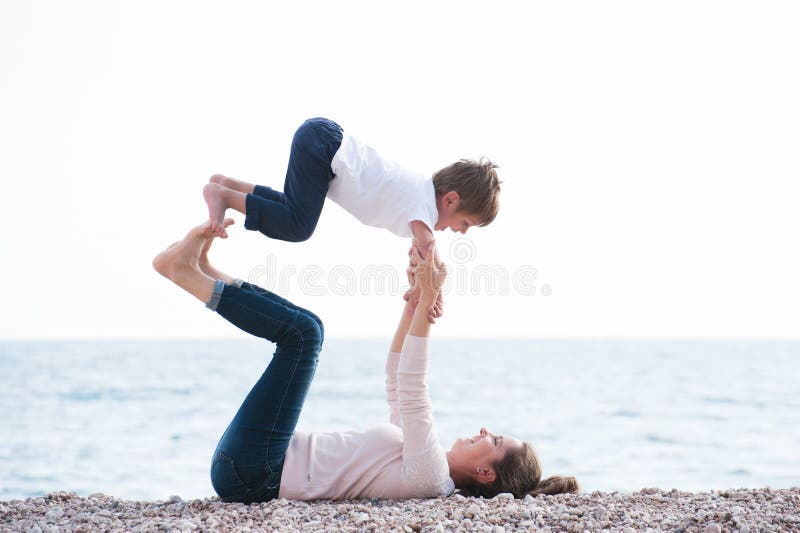 Healthy family playful pretty mother and child making exercises on autumn beach