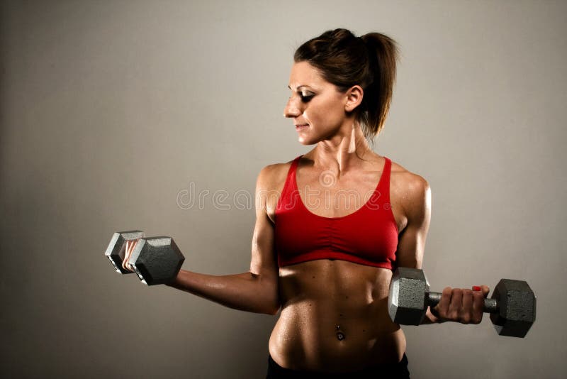 Happy Athletic Woman Flexing Her Bicep At Home High-Res Stock