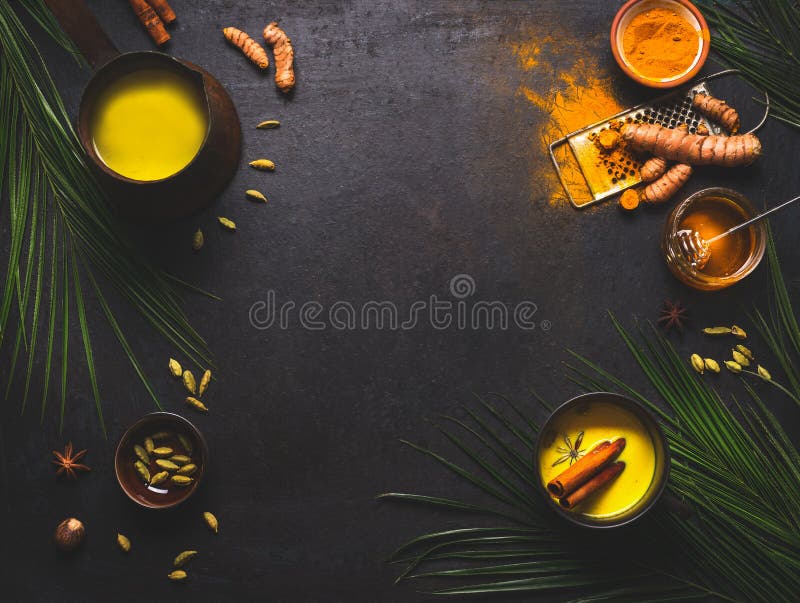 Healthy food background with detox turmeric milk preparation and ingredients on dark background, top view. Copy space. Healthy hot