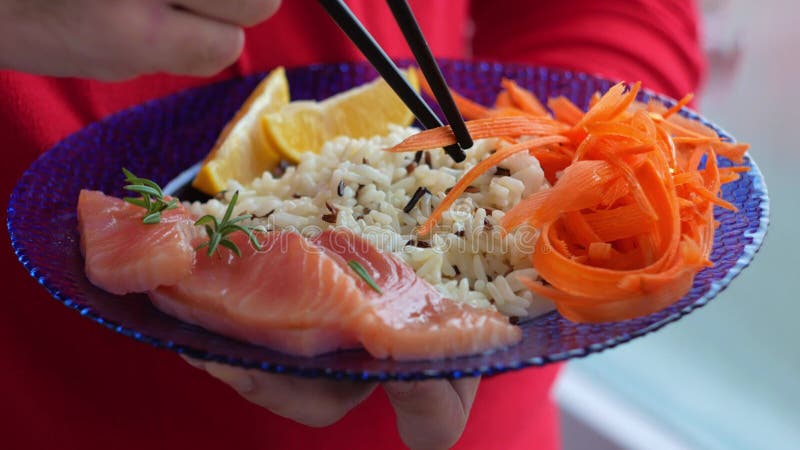 Man Holds Healthy Food Balanced Meal with Salmon Fish Wild Rice Carrots