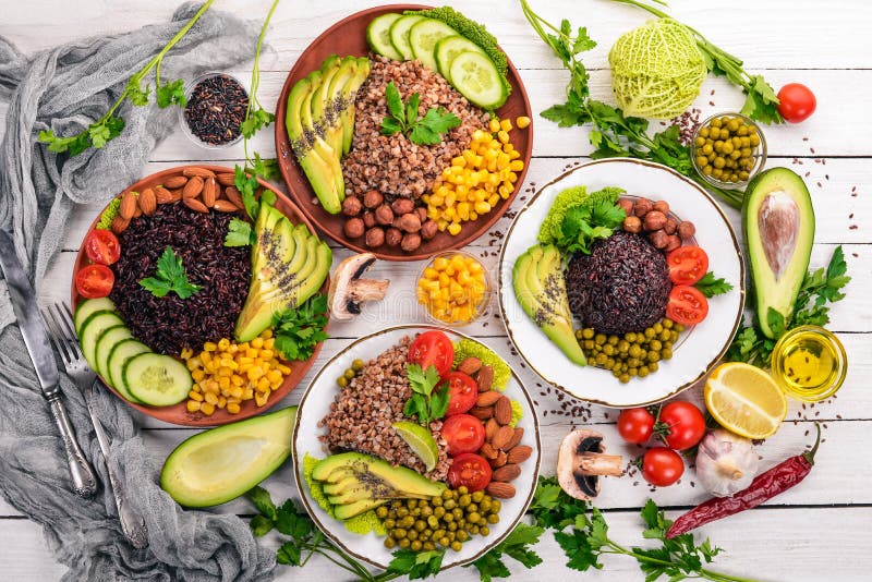 Healthy food. Black rice, buckwheat, avocado, cherry tomatoes, green peas and hazelnut. On a wooden background.