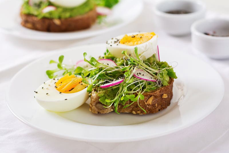 Avocado Egg Sandwich with Whole Grain Bread on White Wooden Background