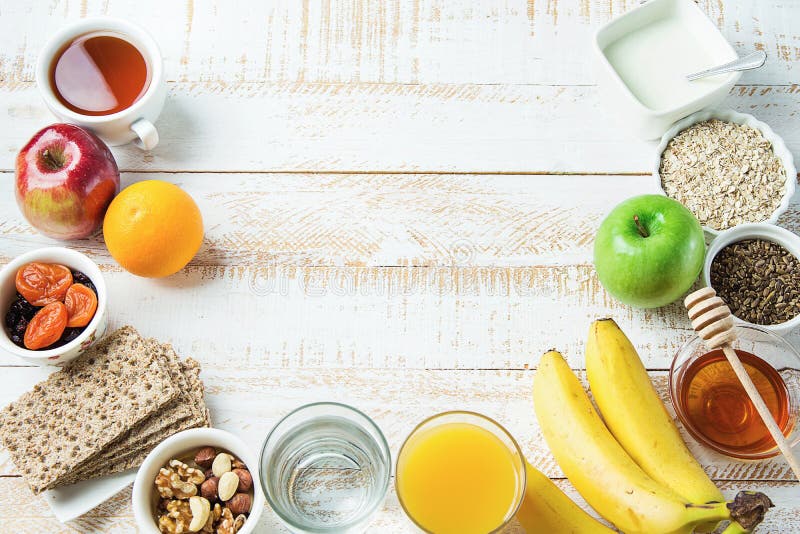 Healthy Food Fiber Sources Breakfast Oatmeal Honey Fruits Apples Banana Orange Juice Water Green Tea Nuts. White Plank Wood Table.