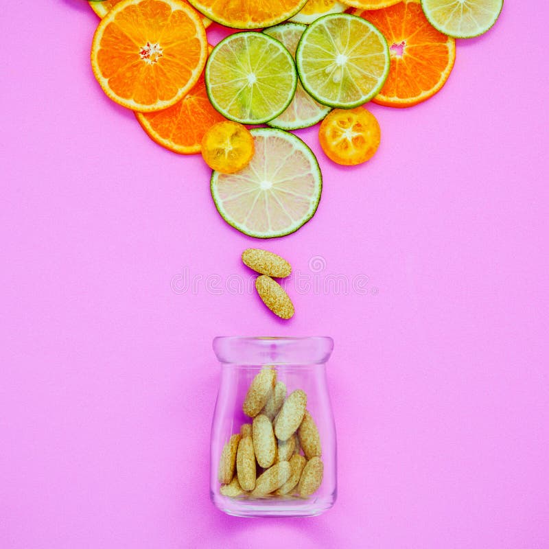 Healthy foods and medicine concept. Bottle of vitamin C and various citrus fruits. Citrus fruits sliced lime,orange and lemon on light pink background flat lay.