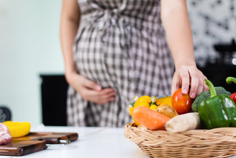 Healthy foods for pregnant women, Young pregnant woman taking fresh tomato royalty free stock image Healthy foods for pregnant women, Young pregnant woman taking fresh tomato royalty free stock image