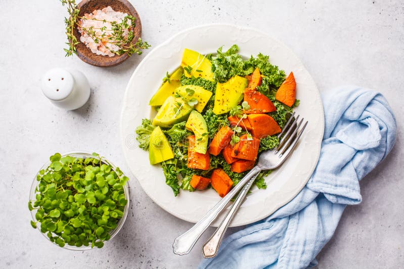Healthy green kale salad with avocado and baked sweet potatoes. Plant based diet concept, detox food