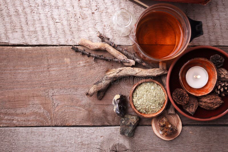 Healthy herbal tea preparation with glass asian teapot, candle. wooden and stone details and vintage rustic wooden background