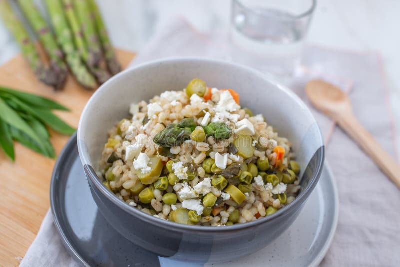 Healthy home made barley soup with spring vegetables, wild garlic and asparagus. On a table