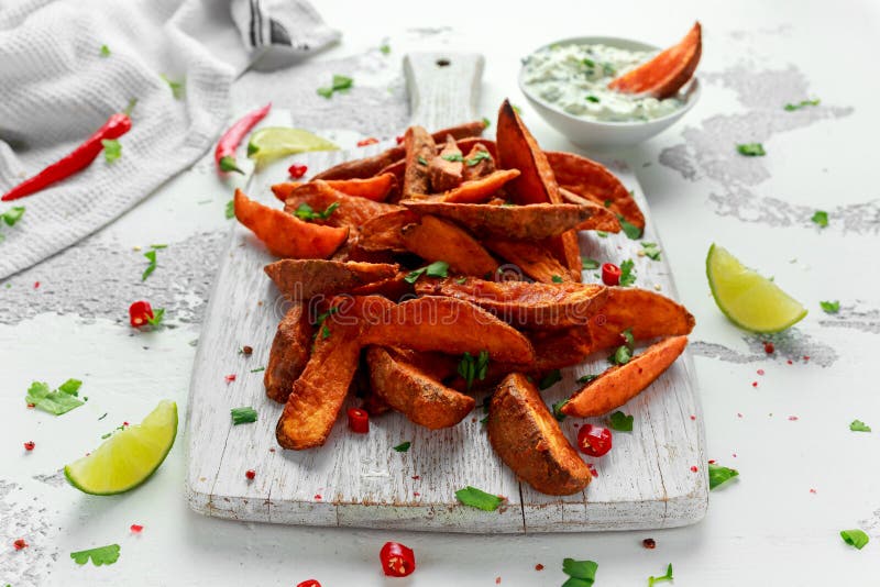 Healthy Homemade Baked Orange Sweet Potato wedges with fresh cream dip sauce, herbs, salt and pepper.