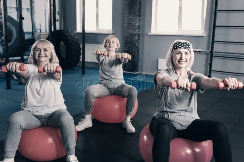 Three elderly ladies holding dumbbells while sitting on exercise balls royalty free stock photos Three elderly ladies holding dumbbells while sitting on exercise balls royalty free stock photos