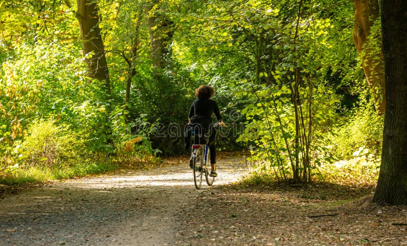 Healthy lifestyle. Woman is riding a bike in a path of Tiergarten park, Berlin, Germany. Nature background