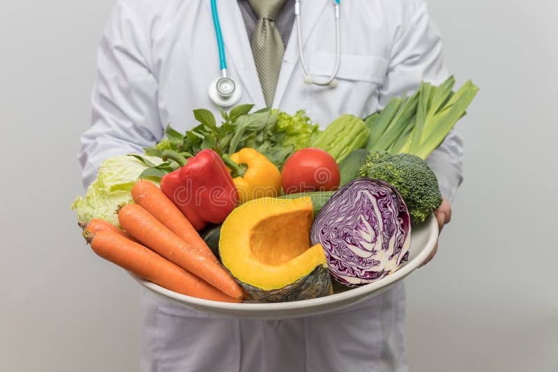 Healthy and nutrition concept. Doctor holding bowl of fresh fruits and vegetables stock photo Healthy and nutrition concept. Doctor holding bowl of fresh fruits and vegetables stock photo