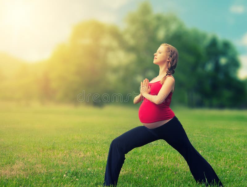 Gesunde schwangere Frau, die yoga in der Natur draußen.