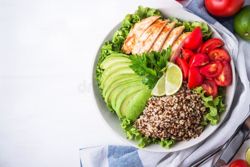 Healthy salad bowl with quinoa, tomatoes, chicken, avocado, lime and mixed greens, lettuce, parsley