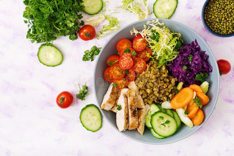 Healthy salad with chicken, tomatoes, cucumber, lettuce, carrot, celery, red cabbage and mung bean on light background.