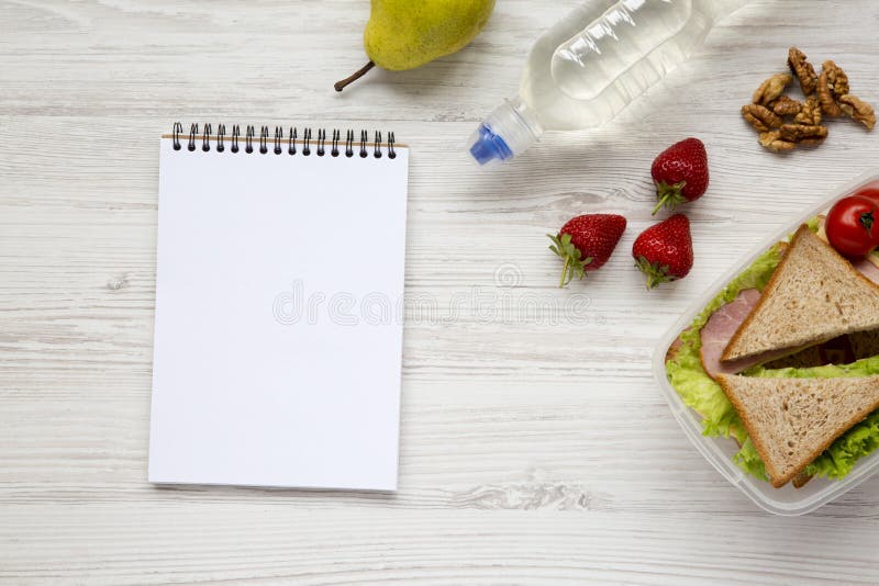 Healthy school lunch box with notebook on white wooden background, flat lay. From above. Top view. stock images Healthy school lunch box with notebook on white wooden background, flat lay. From above. Top view. stock images