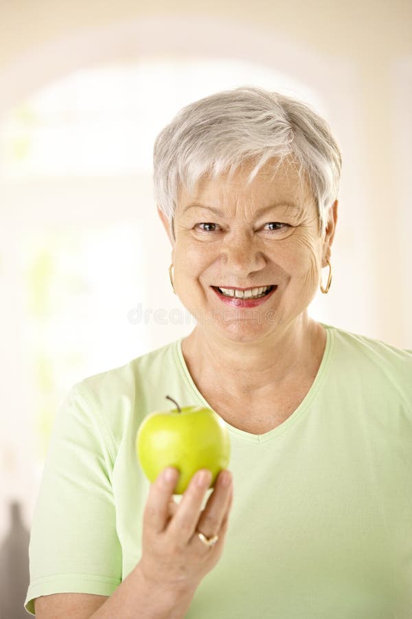 Healthy senior woman holding apple. Closeup portrait of healthy senior woman holding apple, looking at camera, smiling stock photography Healthy senior woman holding apple. Closeup portrait of healthy senior woman holding apple, looking at camera, smiling stock photography