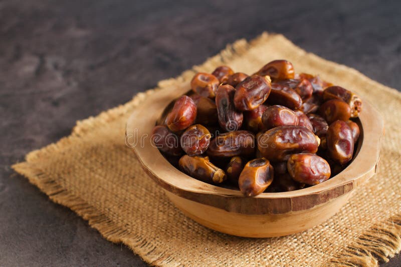 Healthy sweet dried dates fruit in a wooden bowl and on the table. Sweet dried dates fruit in a wooden bowl and on the table royalty free stock image Healthy sweet dried dates fruit in a wooden bowl and on the table. Sweet dried dates fruit in a wooden bowl and on the table royalty free stock image
