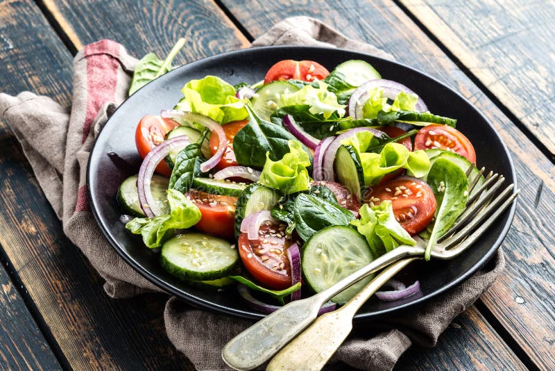 Vegetable salad of fresh tomato, cucumber, spinach, onion and lettuce on plate