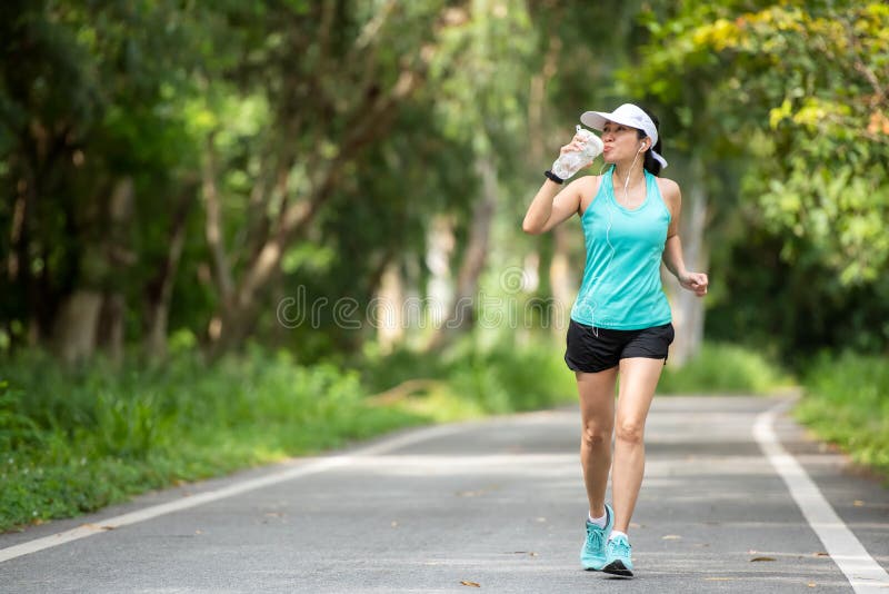 Healthy woman jogging run and workout and drink fresh water on road outdoor. stock photo Healthy woman jogging run and workout and drink fresh water on road outdoor. stock photo