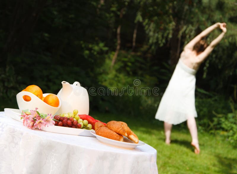 Healthy Woman Stretching Before a Summer Breakfast. A young, fit woman does yoga stretches outdoors before a healthy breakfast on a warm summer morning royalty free stock photos Healthy Woman Stretching Before a Summer Breakfast. A young, fit woman does yoga stretches outdoors before a healthy breakfast on a warm summer morning royalty free stock photos