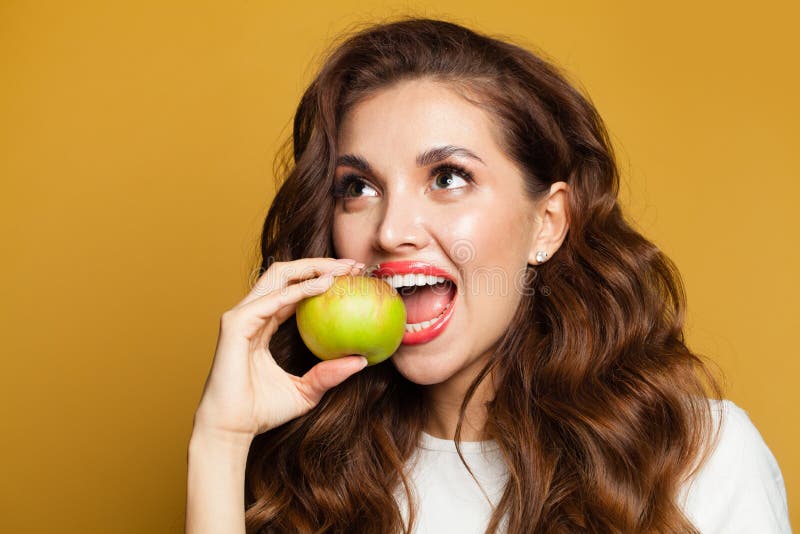 Healthy Woman with White Teeth Biting Apple Fruit on Bright Yellow