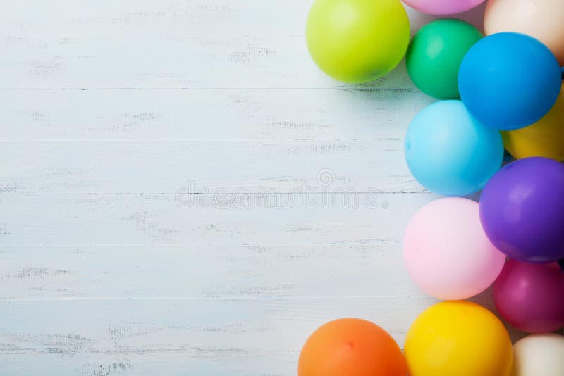 Heap of colorful balloons on blue wooden table top view. Birthday or party background. Flat lay style. Copy space for text. Festive greeting card.