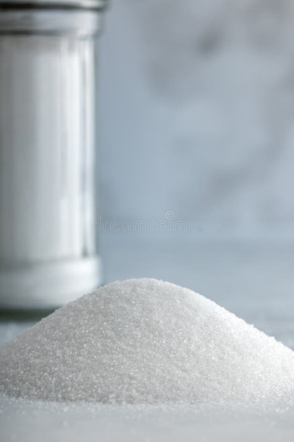 Heap of fine salt and one salt shaker in background on marble countertop stock photos