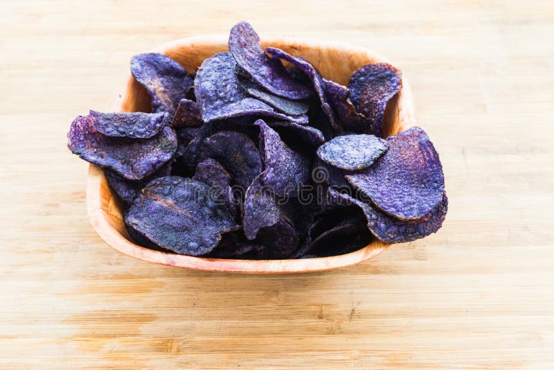 Heap of purple potato chips on wooden background stock image.