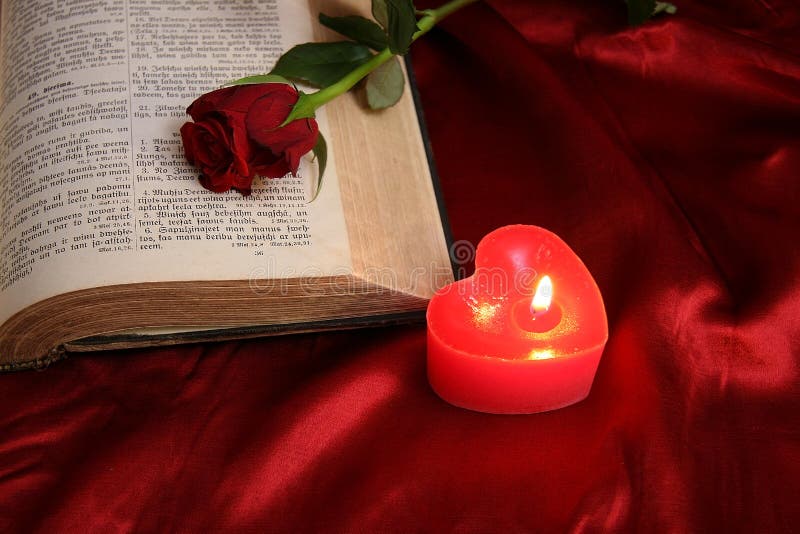 Heart candle on open Bible and red rose