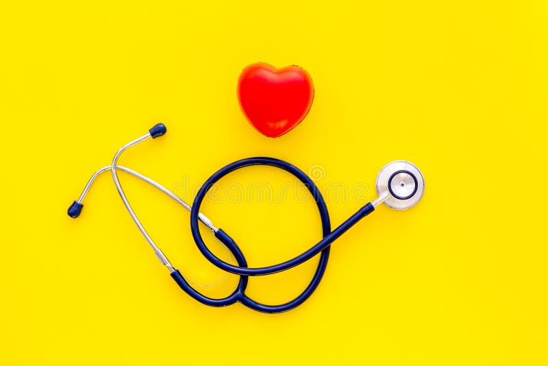 Heart health, health care concept. Stethoscope near rubber heart on yellow background top view copy space royalty free stock images Heart health, health care concept. Stethoscope near rubber heart on yellow background top view copy space royalty free stock images