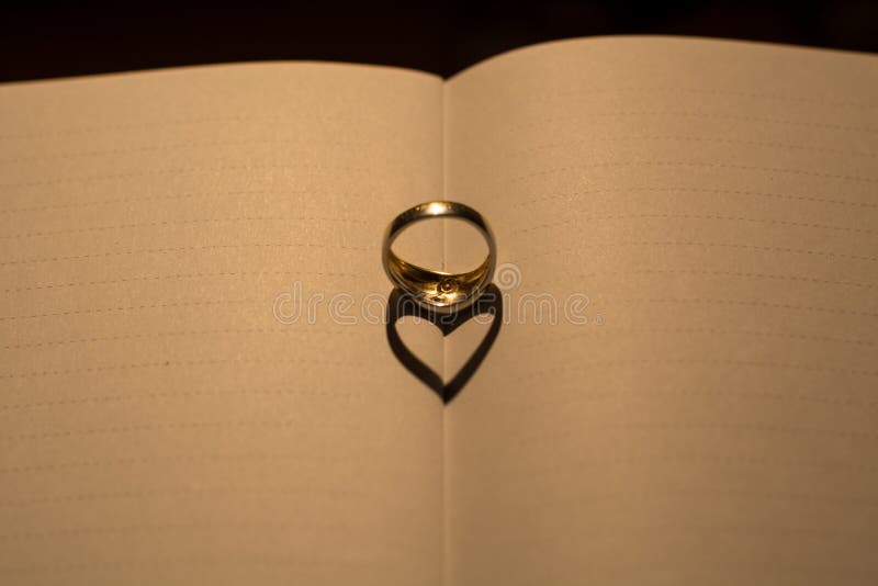 A heart made from the shadow of a ring on a blank book with line stock images