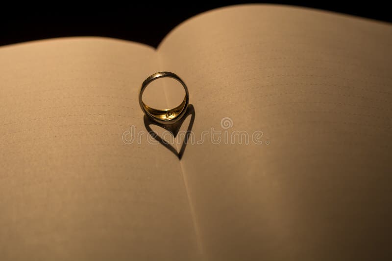 A heart made from the shadow of a ring on a blank book with line royalty free stock images