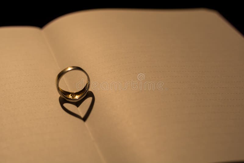 A heart made from the shadow of a ring on a blank book with line stock images