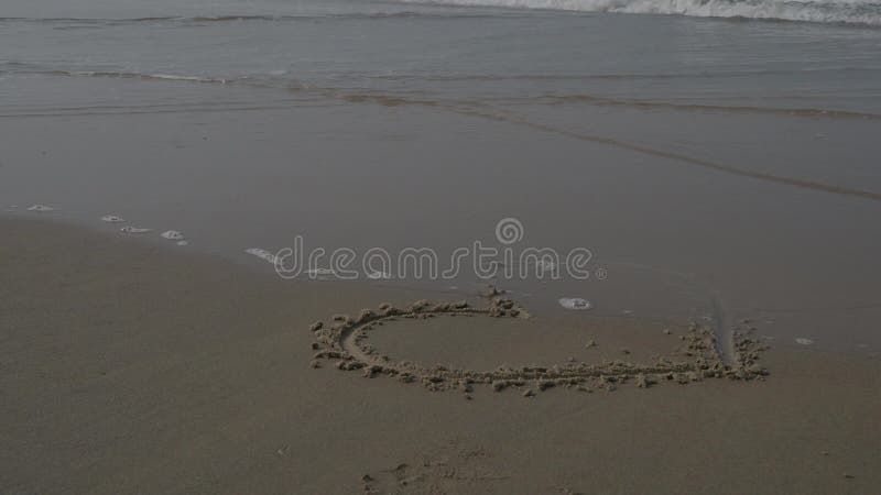 Heart on a sand of beach with wave on background. 4K stock video