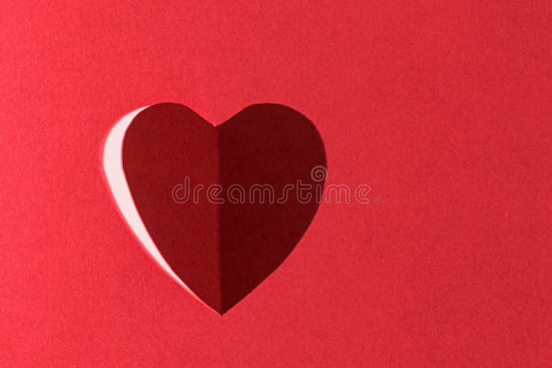 A forma di cuore tagliato in carta rossa e illuminata da parte in modo che l'ombra completa il cuore.