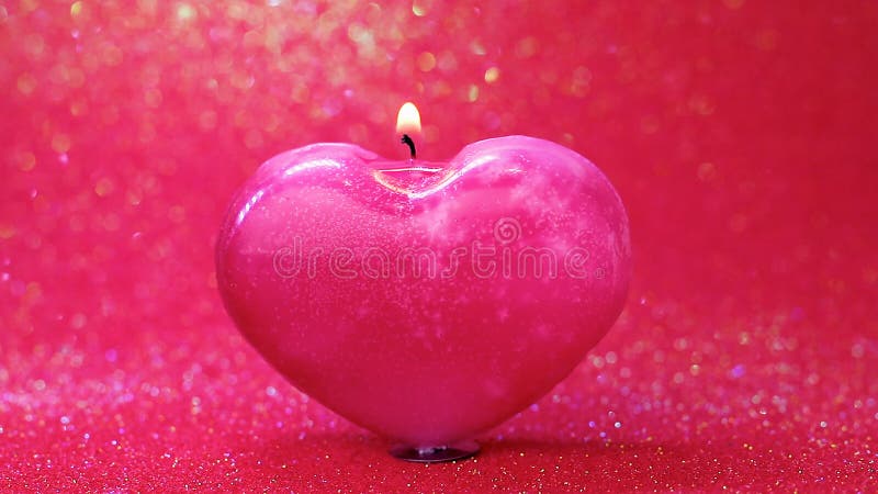 Heart shaped candle burning on a red background with bokeh. Concept valentines day greeting card, banner. Selective focus. Copy