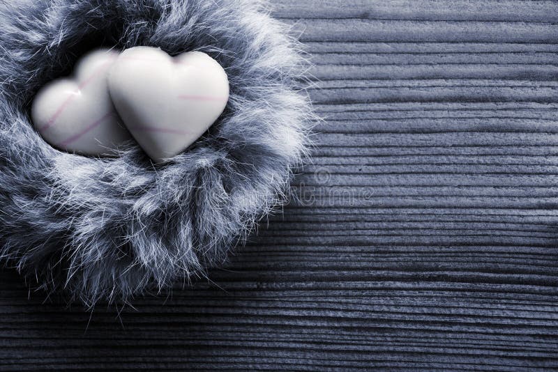 Heart-shaped chocolates in nest, wood background