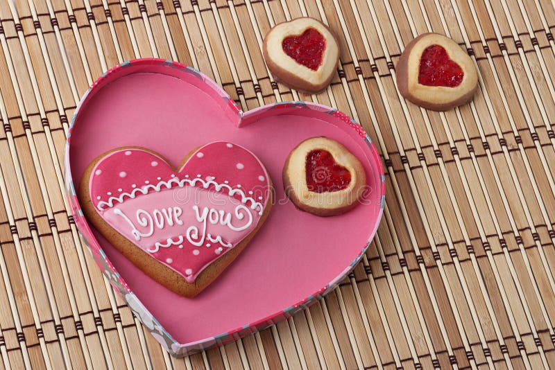 Heart-Shaped Cookies in a Pink Box on an wooden pad.