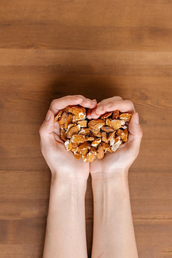 A heart-shaped handful keeps the almond nut. Raw seeds. Waste after cold pressed oil. Love Bio eco organic vegan product. Healthy eating. Oilcake