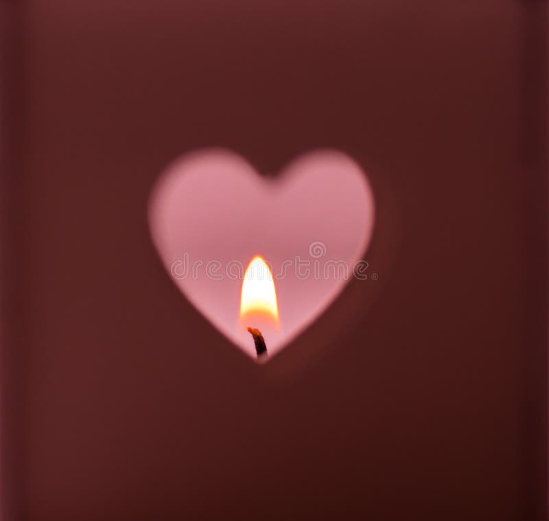 Heart shapes hole cut out on dark red background burning candle light on pink backdrop, romantic, meditation