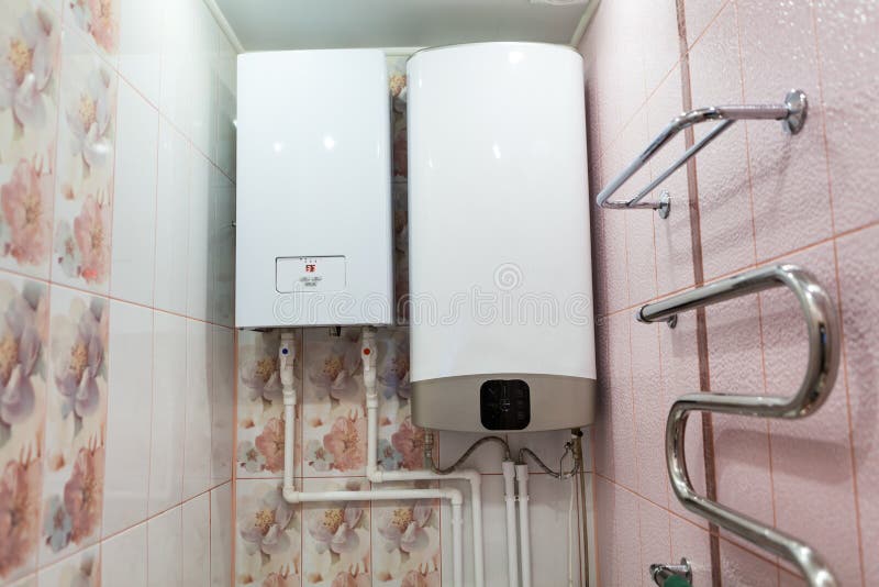 Heat and hot water supply systems are on wall of a bathroom. Electric boiler for central heating and tank for warming water