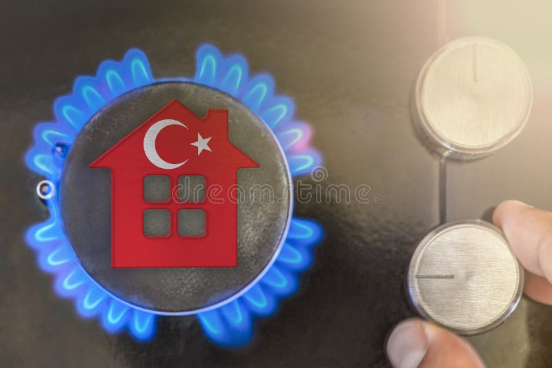 Heating season or gas use in Turkey. Concept, model of a house stands near the flame of a gas boiler on a black