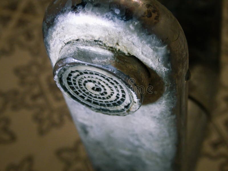 Heavily calcified faucet on a hand basin. Hard water flows from an old tap aerator. Limescale, calcified shower water tap with royalty free stock photo