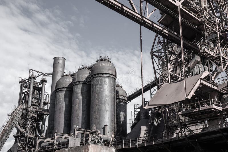 Heavily desaturated view of an industrial steel mill facility with rows of blast furnaces and related structures