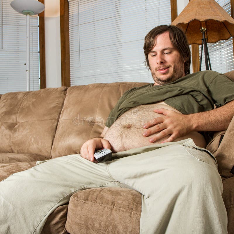 Veľké brucho a muž s úsmevom na to, kým je lenivý s jeho TV remote v ruke.