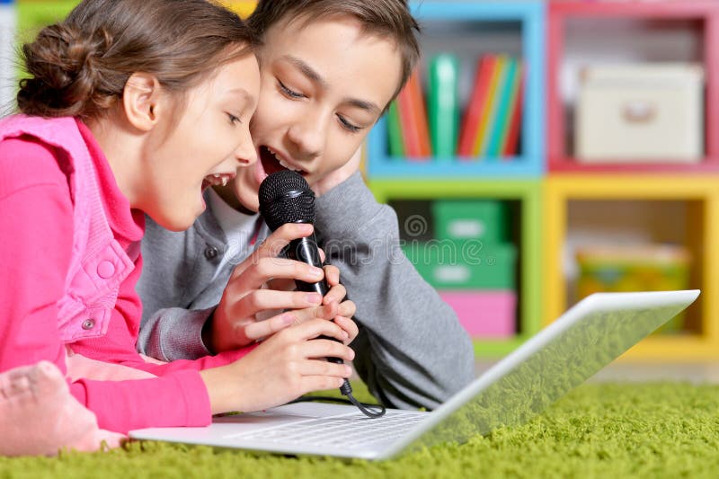Heerlijk meisje en jongen die karaoke zingen met een moderne laptop