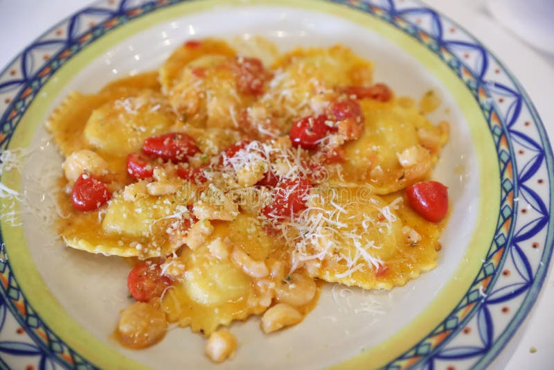 Delicious ravioli and cherry tomatoes on plate from above. lobster ravioli alla vodka. Delicious ravioli and cherry tomatoes on plate from above. lobster ravioli alla vodka.